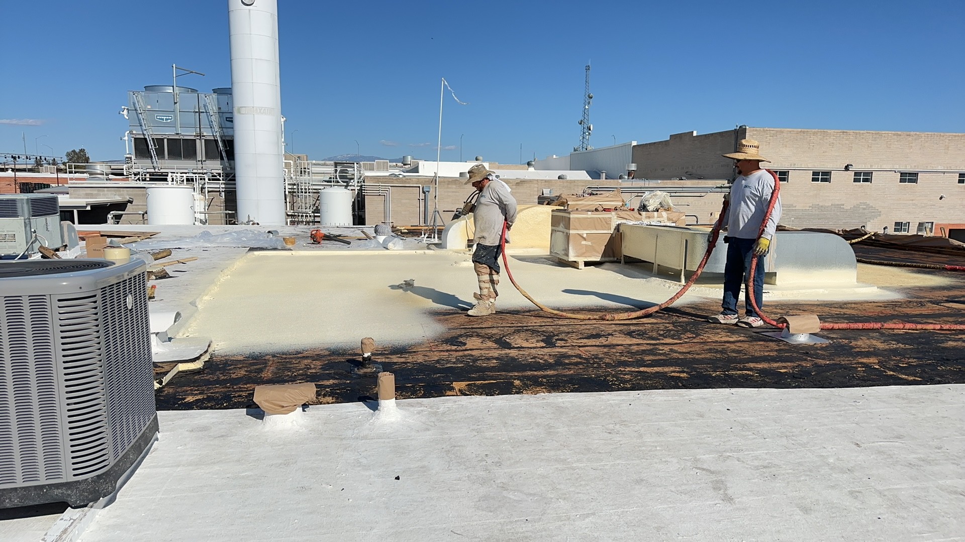 Detail of spray foam being applied around rooftop equipment in Phoenix 85027