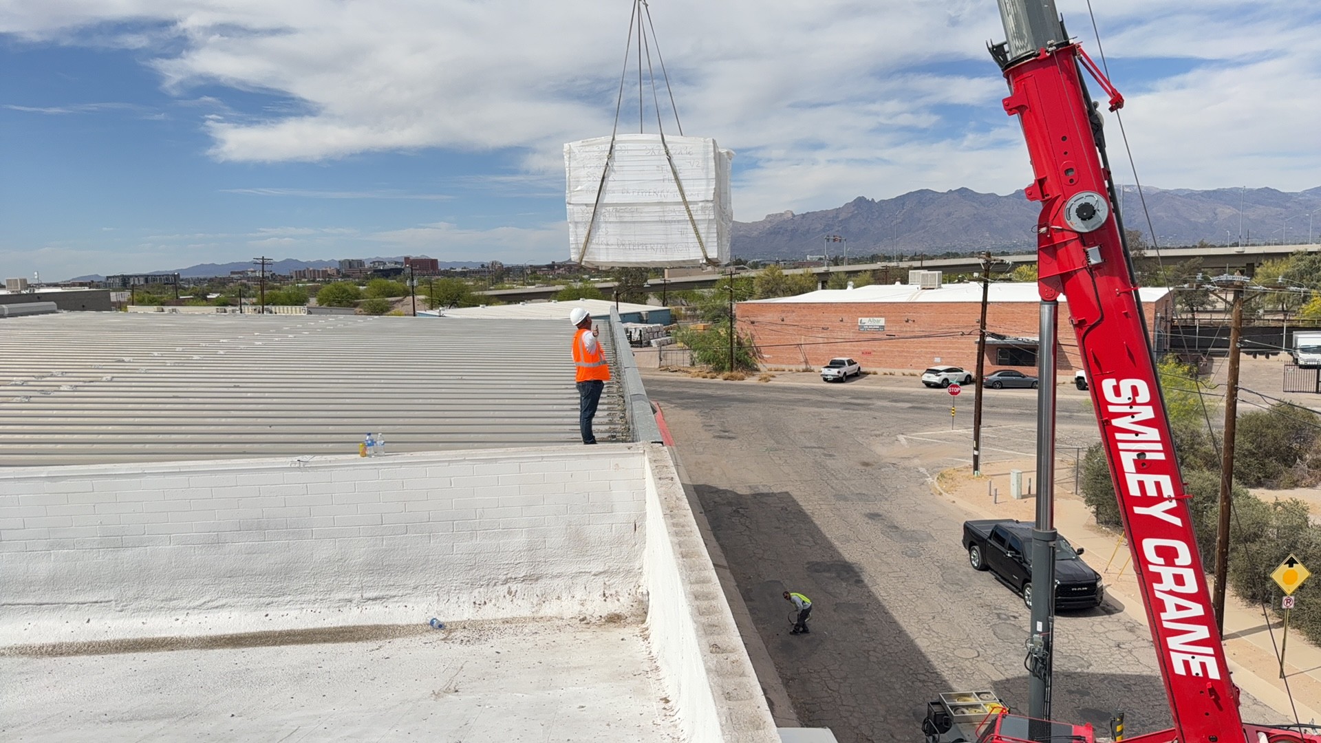 Crane lifting roofing materials onto a commercial building in Tucson 85719