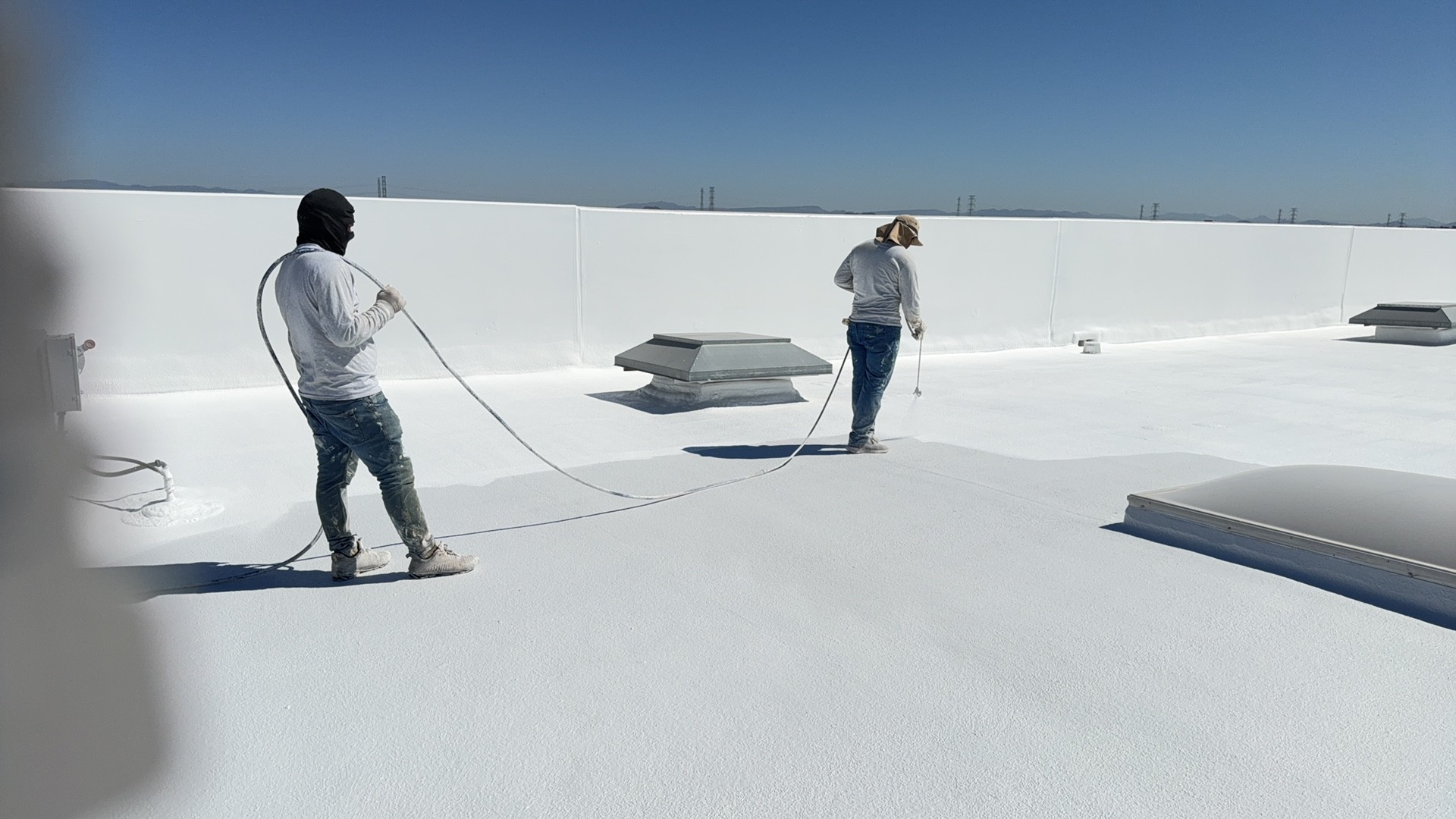 Crew applying white reflective coating to a commercial roof in Glendale 85307