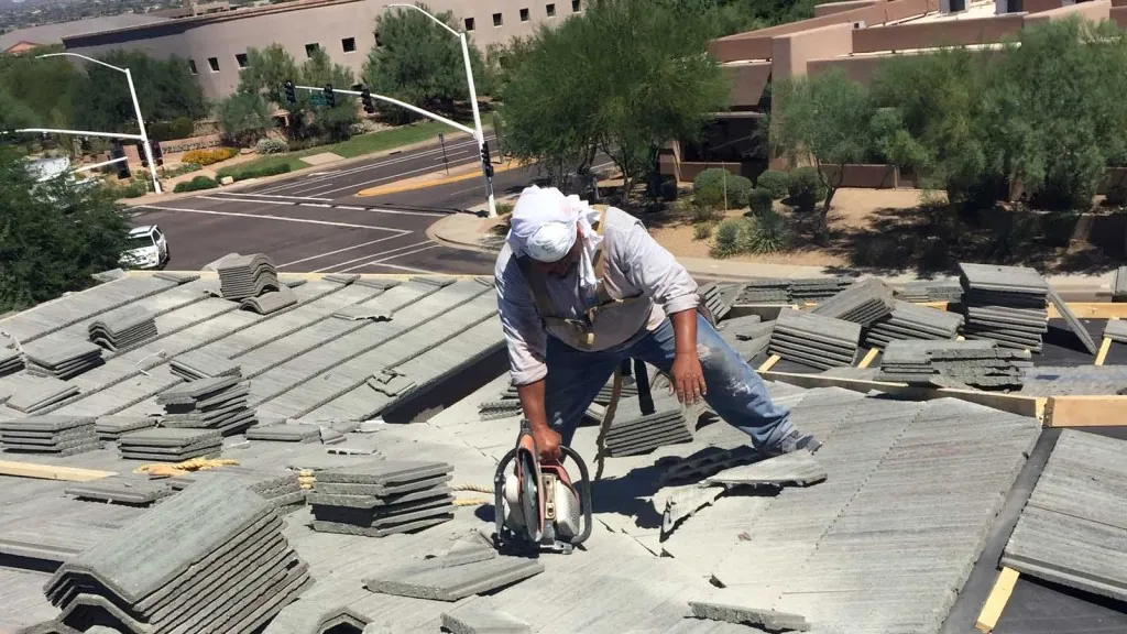 A KY-KO Roofing specialist uses a tool to cut tile before positioning it on the roof of this apartment building.