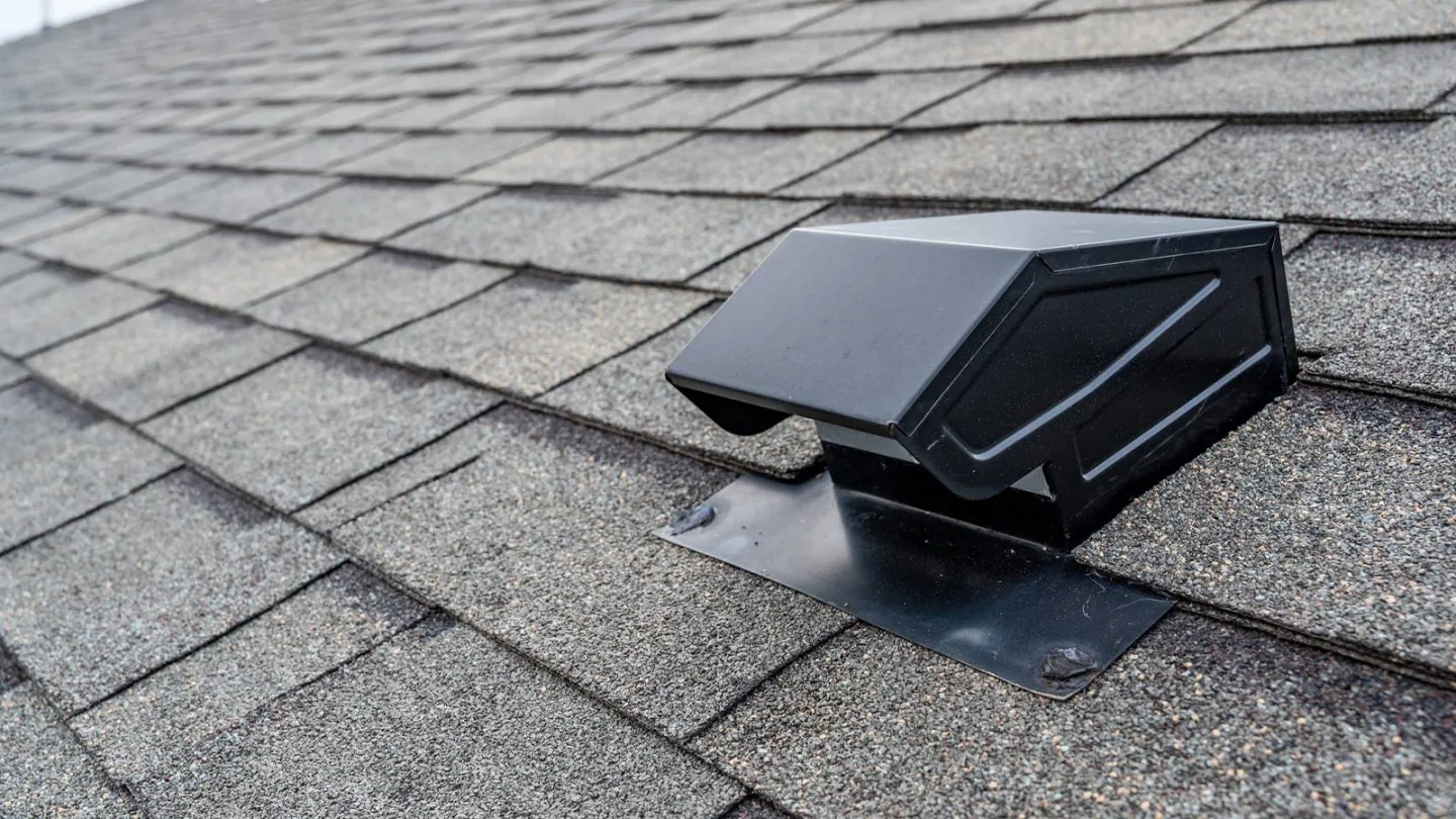 A black roof vent installed on a shingle roof.