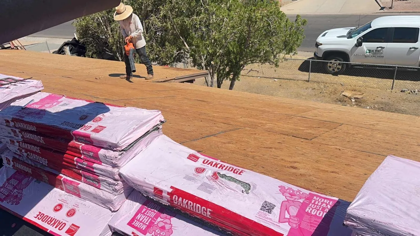 A roofer is blowing the dust off of a plywood roof that he is about to shingle.